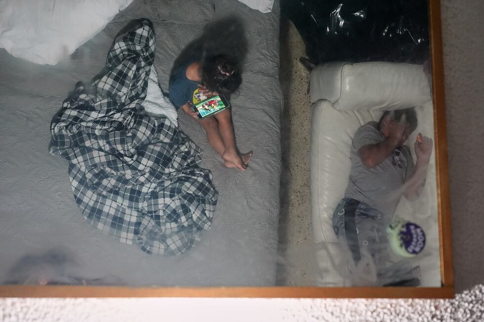 La imagen de dos hermanos se refleja en el espejo del techo de la habitación de motel donde...