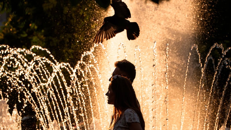 Una pareja pasa por una fuente pública en un día caluroso, en el que la agencia Nacional de...