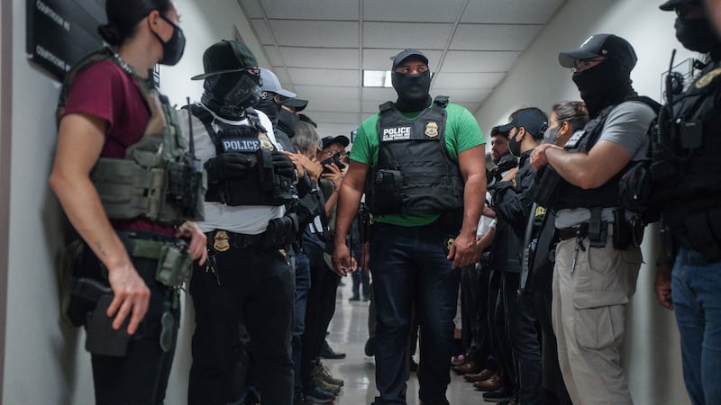 ARCHIVO - Agentes federales enmascarados esperan afuera de una sala de audiencias de...