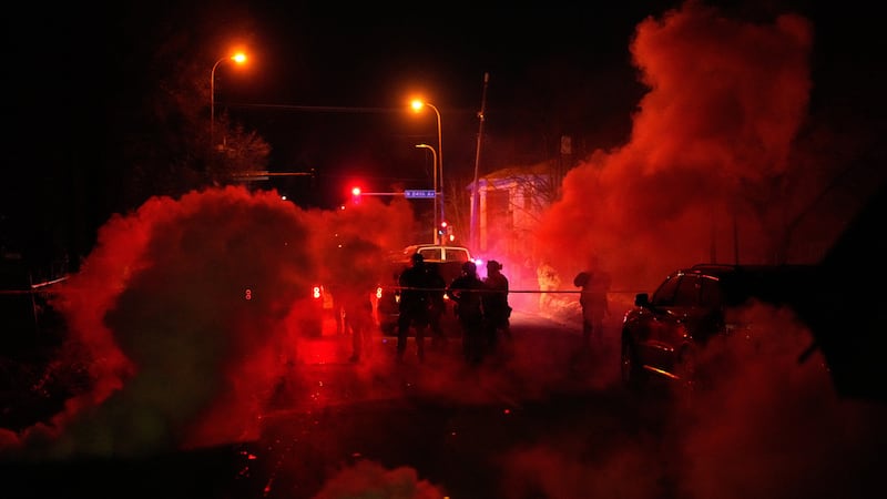 Agentes federales rodeados de gas lacrimógeno salen del sitio de un tiroteo, el miércoles 14...