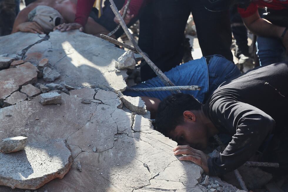 Residentes y equipos de rescate buscan entre los escombros de un edificio derrumbado tras el...