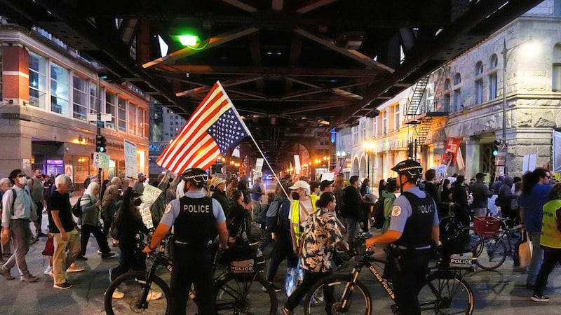 ARCHIVO - Agentes de policía cortan una calle mientras manifestantes participan en una...