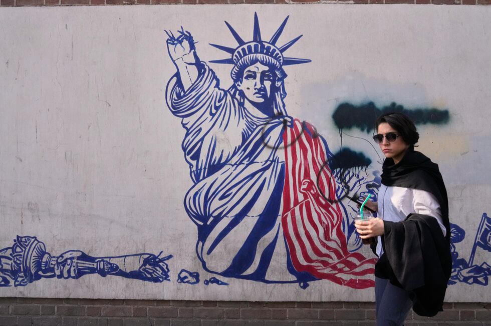 Una mujer pasa junto a un mural antiestadounidense en la pared de la antigua embajada de...