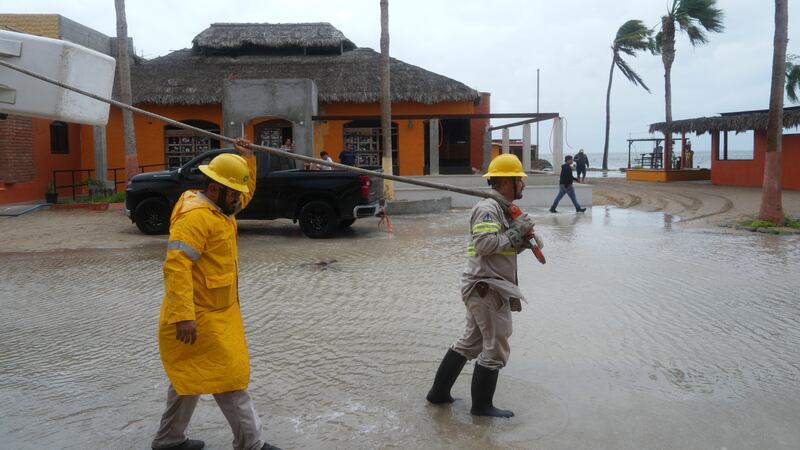 Trabajadores remolcan una embarcación a tierra mientras el huracán Polo se aproxima a Puerto...