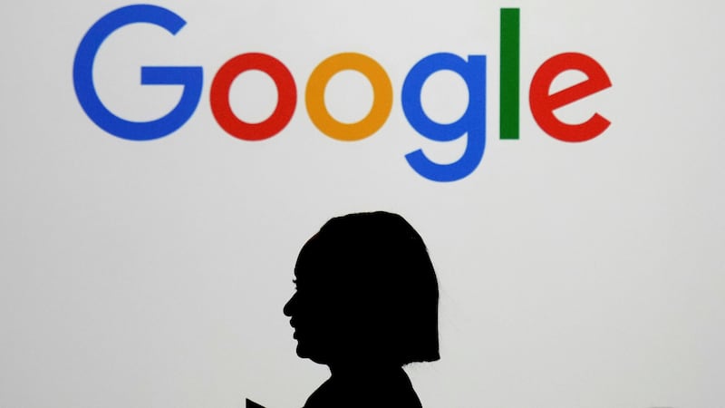 ARCHIVO – Una mujer camina frente a una pantalla gigante con el logotipo de Google en un...