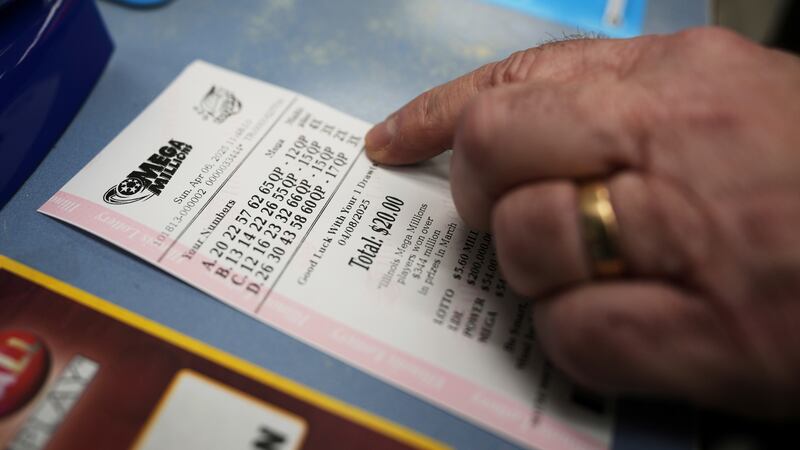 Pete Gruber points a Mega Millions lottery ticket after he purchased at Mares Mart in Chicago,...